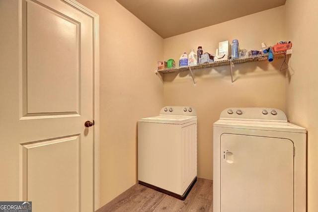 clothes washing area featuring washer and clothes dryer, light wood-style floors, and laundry area