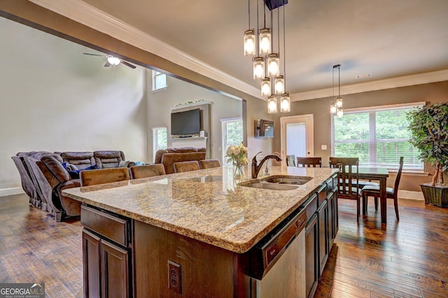 kitchen with a sink, hanging light fixtures, light stone counters, and dishwasher