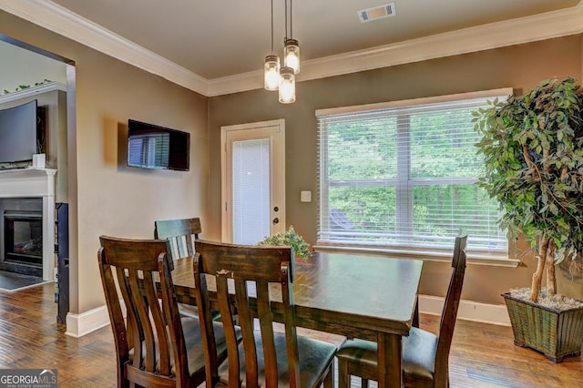 dining area featuring wood finished floors, baseboards, ornamental molding, and visible vents