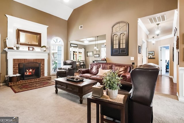 living room featuring a fireplace, high vaulted ceiling, carpet, and visible vents