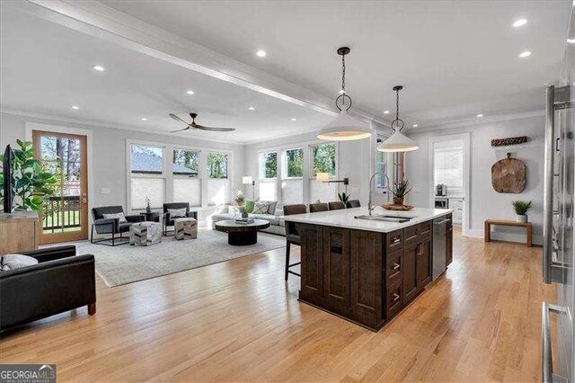 kitchen with dark brown cabinetry, ornamental molding, a breakfast bar, open floor plan, and light wood finished floors