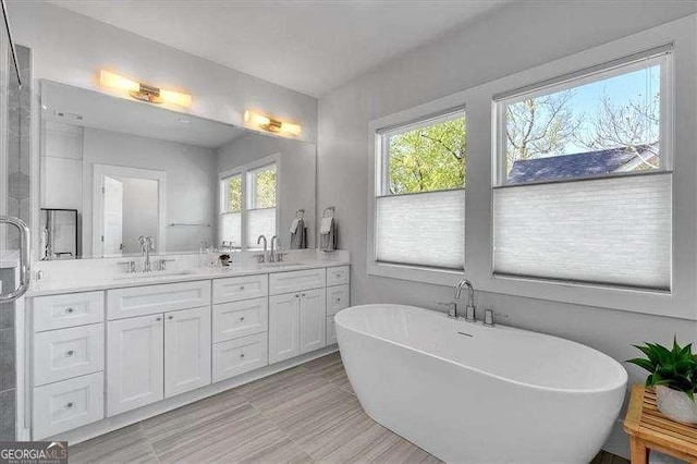 full bath with a sink, double vanity, and a soaking tub