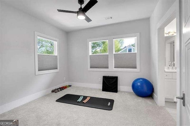 exercise room with light colored carpet, ceiling fan, baseboards, and visible vents