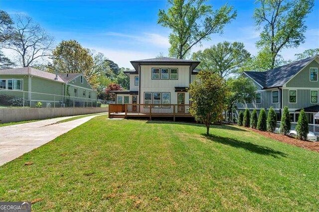 back of property with a yard, board and batten siding, fence, and a wooden deck