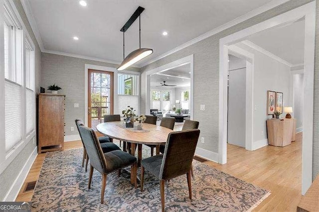 dining area with ornamental molding, light wood-style flooring, visible vents, and baseboards