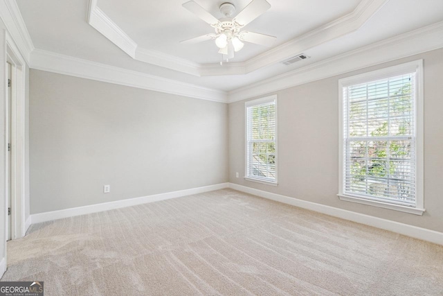 spare room with light carpet, visible vents, a tray ceiling, and ornamental molding