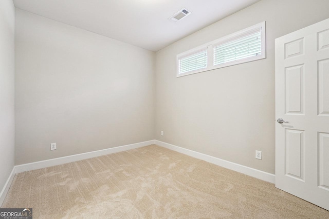 empty room with light colored carpet, baseboards, and visible vents
