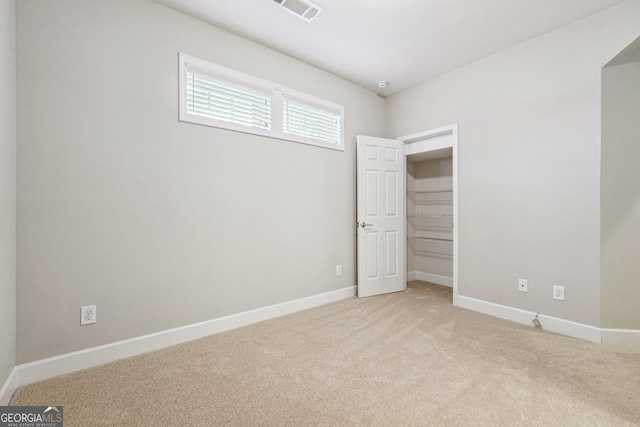 unfurnished bedroom featuring a closet, light colored carpet, baseboards, and visible vents