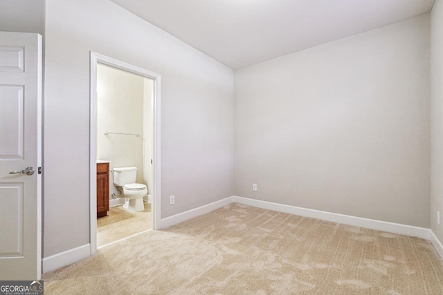 unfurnished bedroom featuring light carpet, ensuite bath, and baseboards