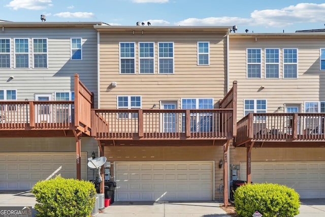 rear view of property featuring a garage, central AC unit, and driveway