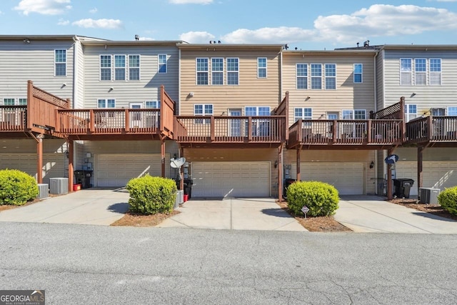 rear view of property with driveway, cooling unit, and a garage