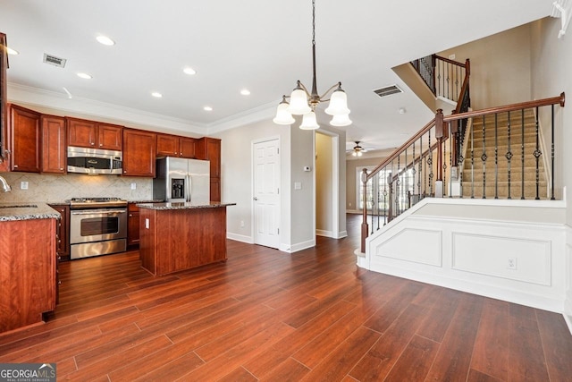 kitchen featuring a center island, dark wood-style flooring, crown molding, stainless steel appliances, and decorative backsplash