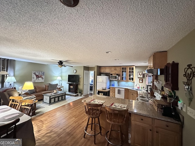 80 Hill Farm Rd, Alamo, GA 30411 - kitchen with a peninsula, a sink, white appliances, glass insert cabinets, and brown cabinets