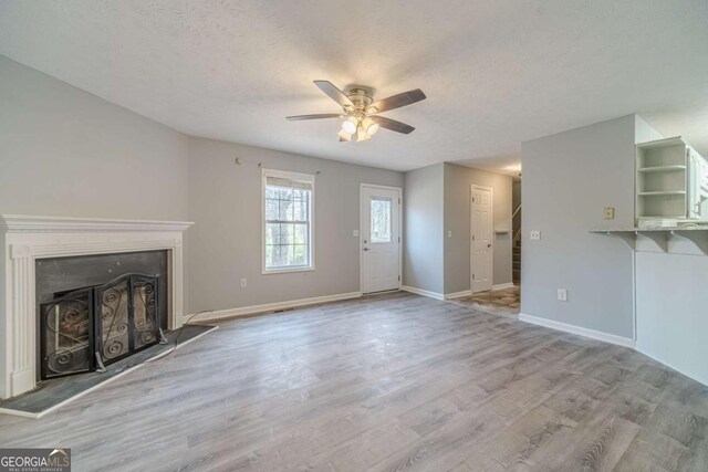 29 Monte Ln, Jefferson, GA 30549 - unfurnished living room with ceiling fan, wood finished floors, a fireplace with raised hearth, and a textured ceiling