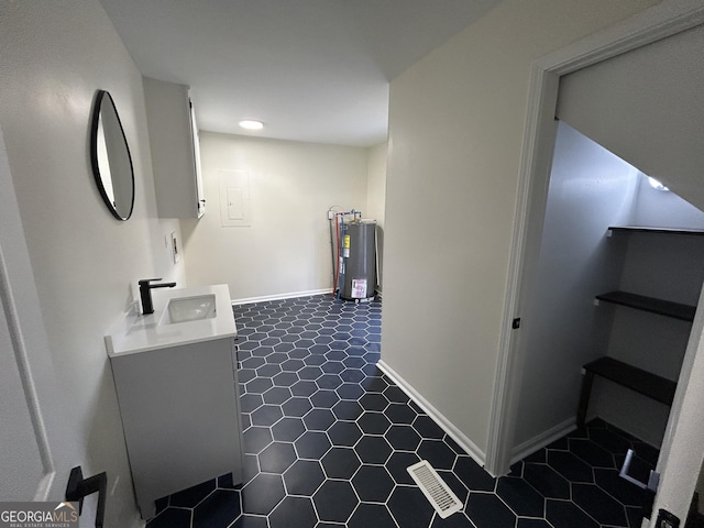 22 Edgewood Dr, Carrollton, GA 30116 - laundry area featuring dark tile patterned flooring, visible vents, water heater, a sink, and baseboards