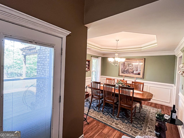 dining space featuring crown molding, a tray ceiling, a chandelier, and wood finished floors