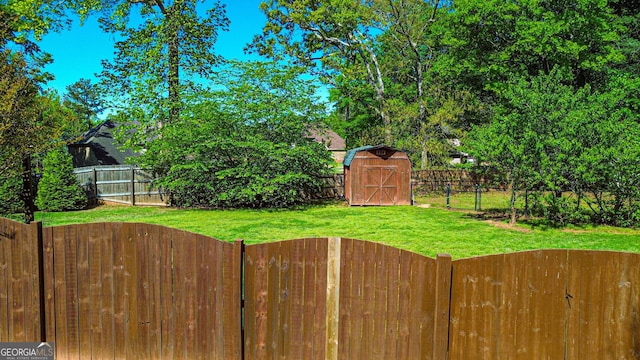 view of yard featuring a shed, a fenced backyard, and an outbuilding