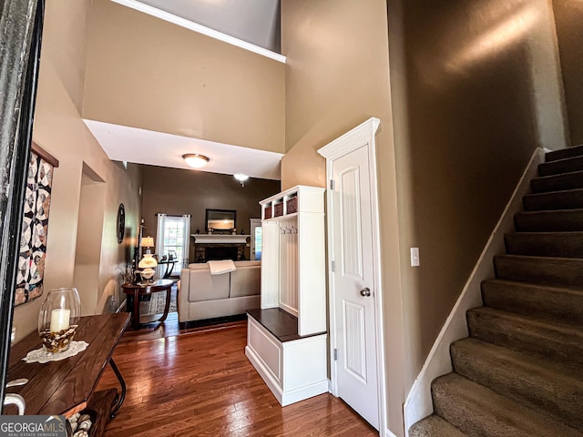 entrance foyer with a fireplace, stairway, dark wood-style floors, and a high ceiling