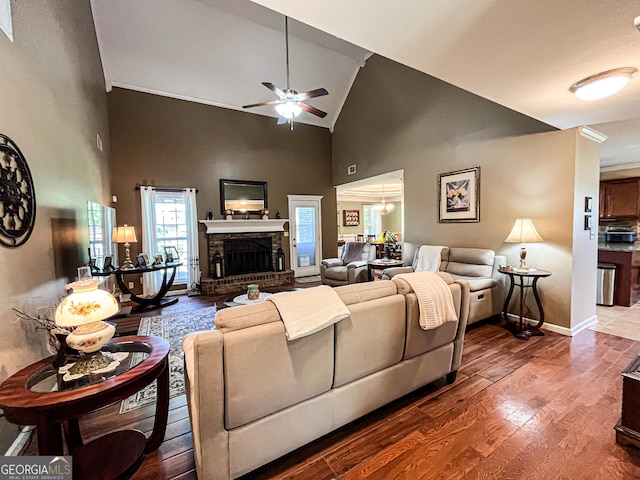 living area with baseboards, a fireplace, ceiling fan, high vaulted ceiling, and wood finished floors
