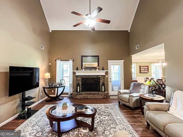 living room featuring crown molding, ceiling fan with notable chandelier, a fireplace, a high ceiling, and wood finished floors