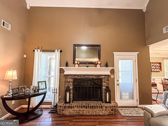 living room featuring visible vents, baseboards, a fireplace with raised hearth, and wood finished floors
