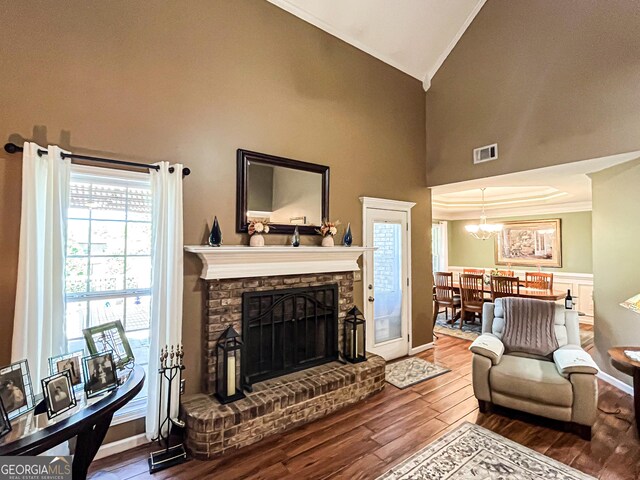 living area featuring crown molding, wood finished floors, a fireplace with raised hearth, and visible vents