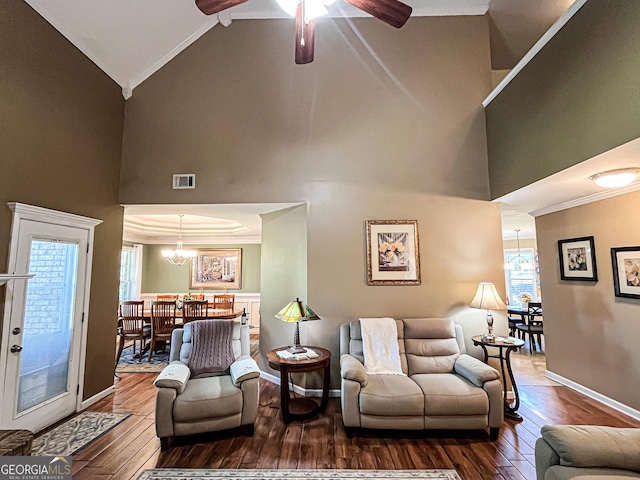 living area featuring visible vents, a wealth of natural light, hardwood / wood-style flooring, crown molding, and high vaulted ceiling