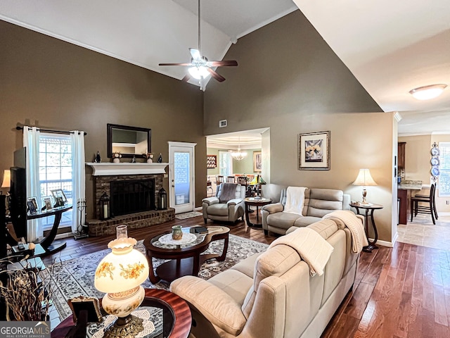 living area with dark wood-type flooring, a fireplace with raised hearth, ceiling fan with notable chandelier, and baseboards