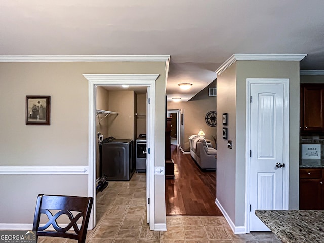 corridor featuring ornamental molding, baseboards, washer and dryer, and visible vents