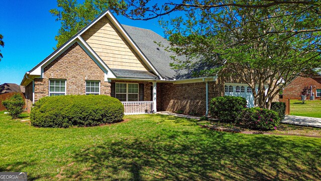 view of front of home with covered porch, a front yard, and stone siding