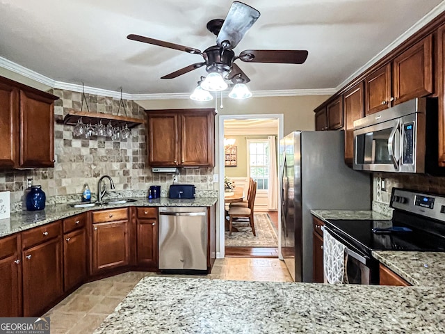 kitchen with light stone countertops, ceiling fan, a sink, and appliances with stainless steel finishes