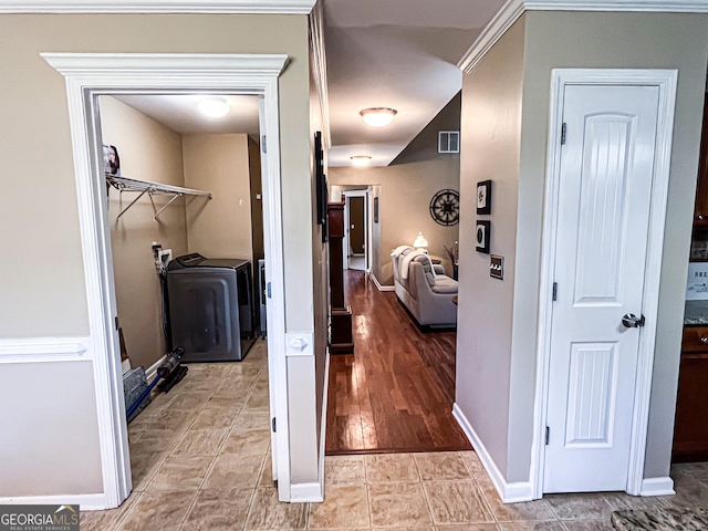 hall with independent washer and dryer, visible vents, and baseboards
