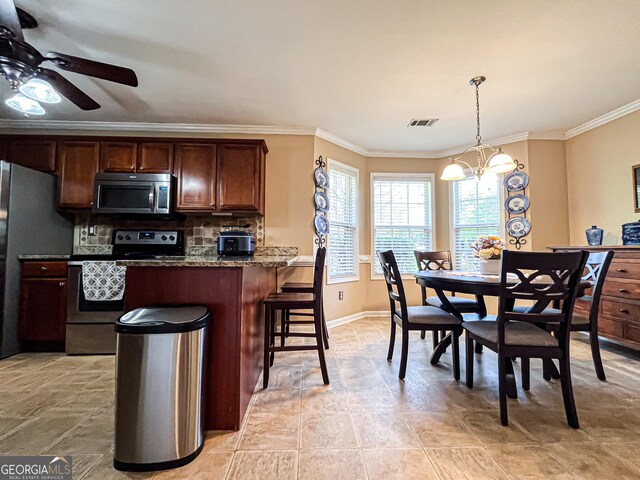 kitchen featuring ceiling fan with notable chandelier, ornamental molding, visible vents, stainless steel appliances, and backsplash