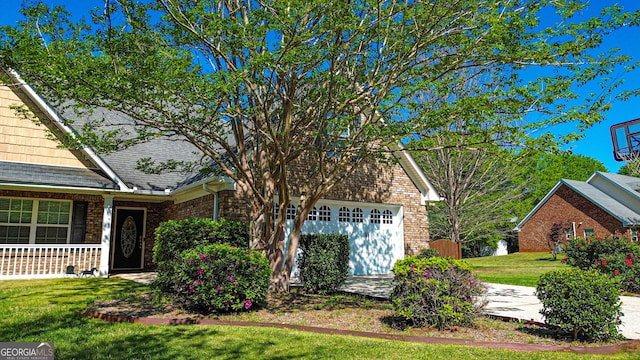 view of front facade with brick siding, a front lawn, a garage, and roof with shingles