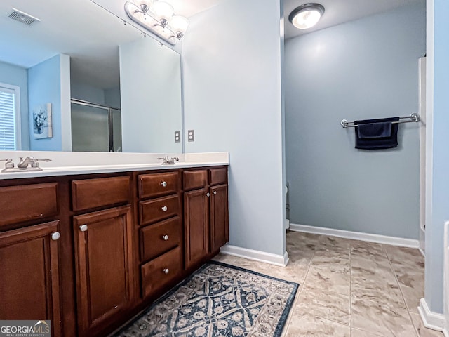 full bath featuring a sink, baseboards, double vanity, and a stall shower