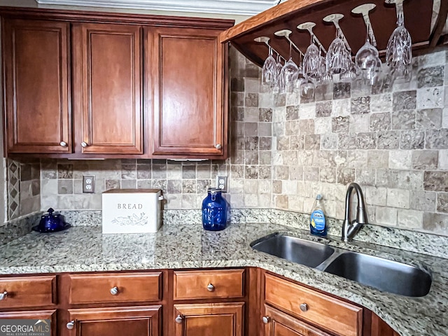 kitchen with tasteful backsplash, light stone counters, and a sink