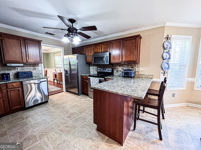 kitchen featuring a kitchen breakfast bar, plenty of natural light, a ceiling fan, visible vents, and appliances with stainless steel finishes
