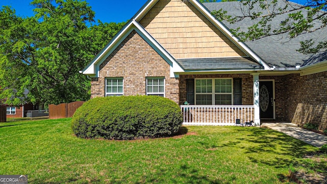 view of front facade with a porch, fence, and a front lawn