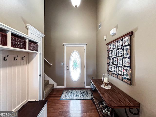 entrance foyer featuring a towering ceiling, baseboards, stairway, dark wood-type flooring, and visible vents