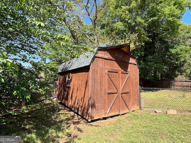 view of barn with a yard and fence