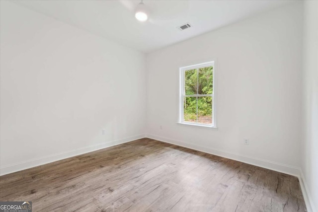 empty room featuring visible vents, baseboards, and wood finished floors