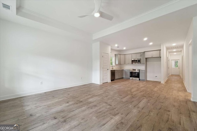 unfurnished living room with visible vents, ornamental molding, a ceiling fan, a healthy amount of sunlight, and light wood finished floors