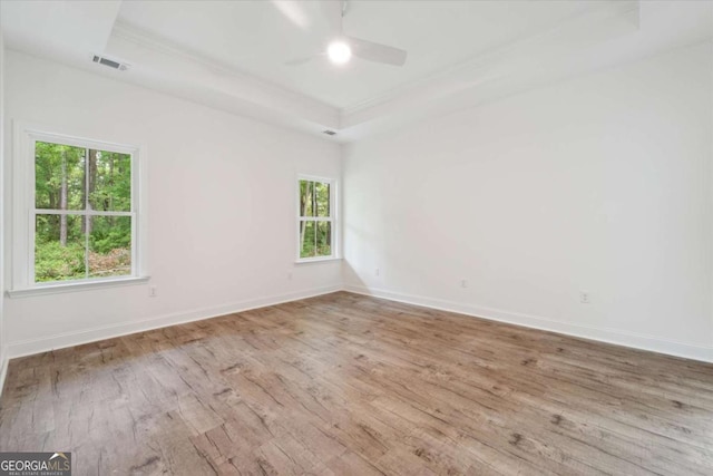 empty room featuring wood-type flooring, a ceiling fan, and a healthy amount of sunlight