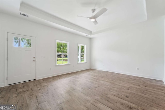 foyer featuring a raised ceiling, wood finished floors, baseboards, and visible vents
