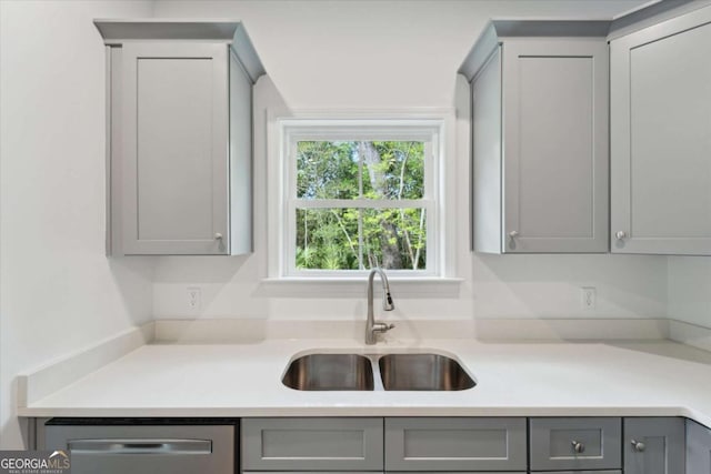 kitchen featuring dishwasher, light countertops, a sink, and gray cabinets