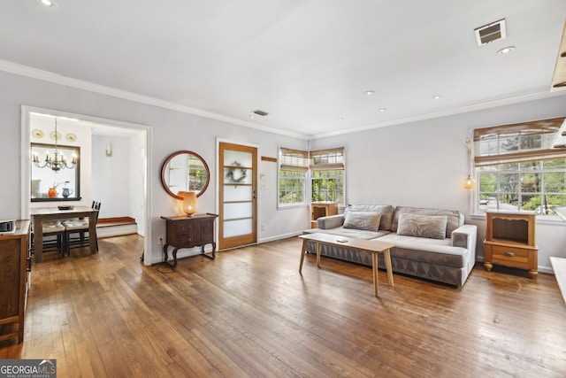 living room with hardwood / wood-style floors, an inviting chandelier, ornamental molding, and visible vents