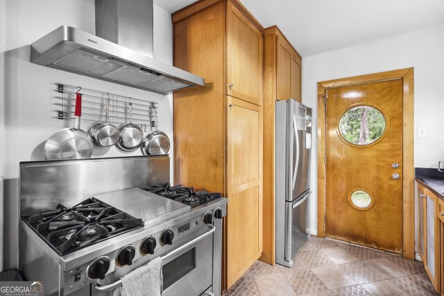 kitchen featuring stainless steel appliances, brown cabinetry, light tile patterned flooring, and ventilation hood