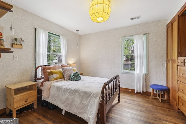 bedroom with visible vents, hardwood / wood-style flooring, and wallpapered walls