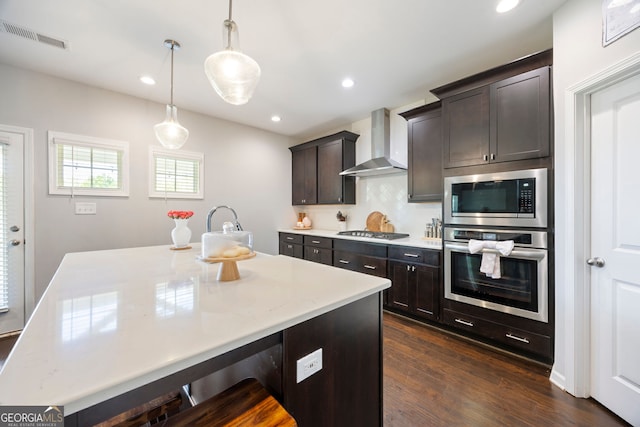 32 Winifred Way, Senoia, GA 30276 - kitchen with stainless steel appliances, wall chimney exhaust hood, dark wood-style flooring, decorative light fixtures, and dark brown cabinetry