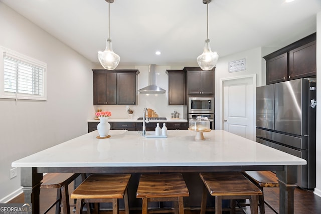 32 Winifred Way, Senoia, GA 30276 - kitchen with appliances with stainless steel finishes, wall chimney exhaust hood, dark brown cabinets, a kitchen breakfast bar, and a center island with sink